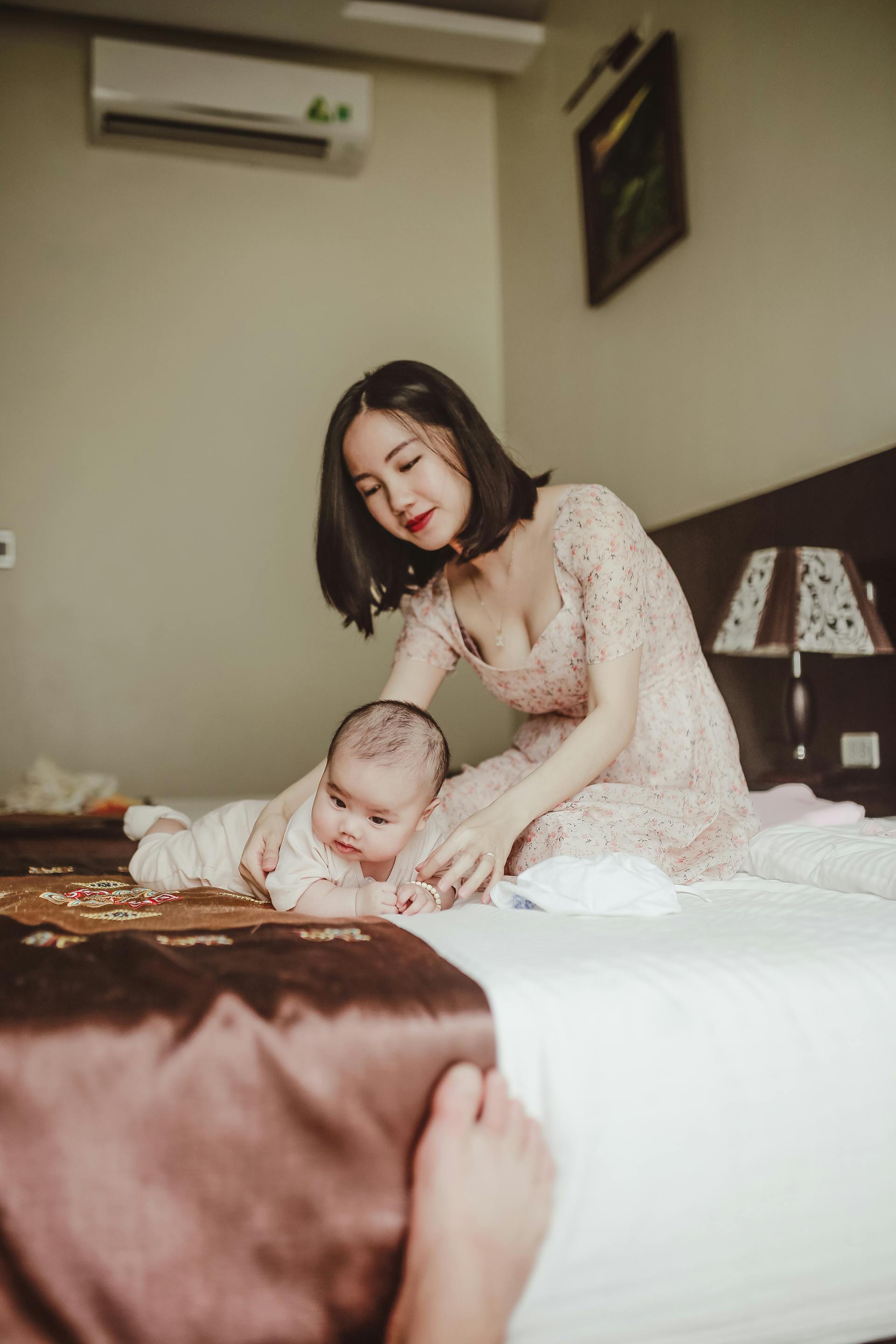 Asian mother with her baby on the bed
