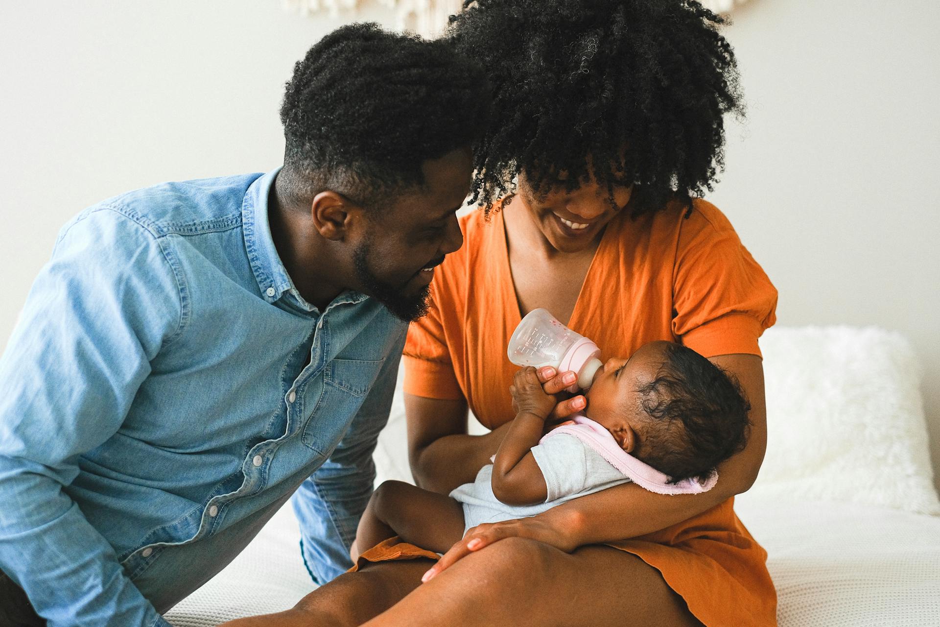 Black family together feeding their newborn baby